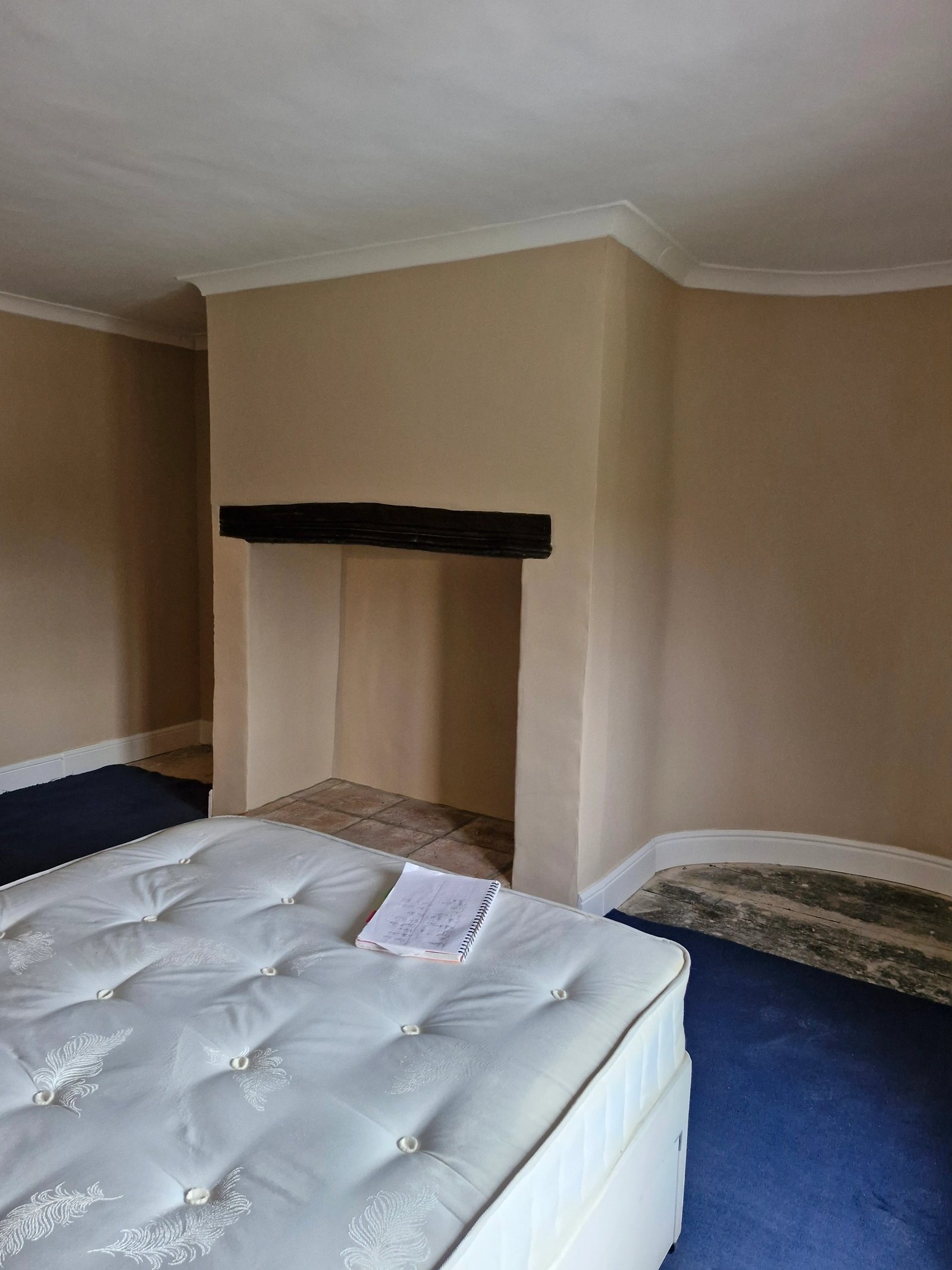 Bedroom mid-refurbishment with an exposed timber lintel over the chimney breast