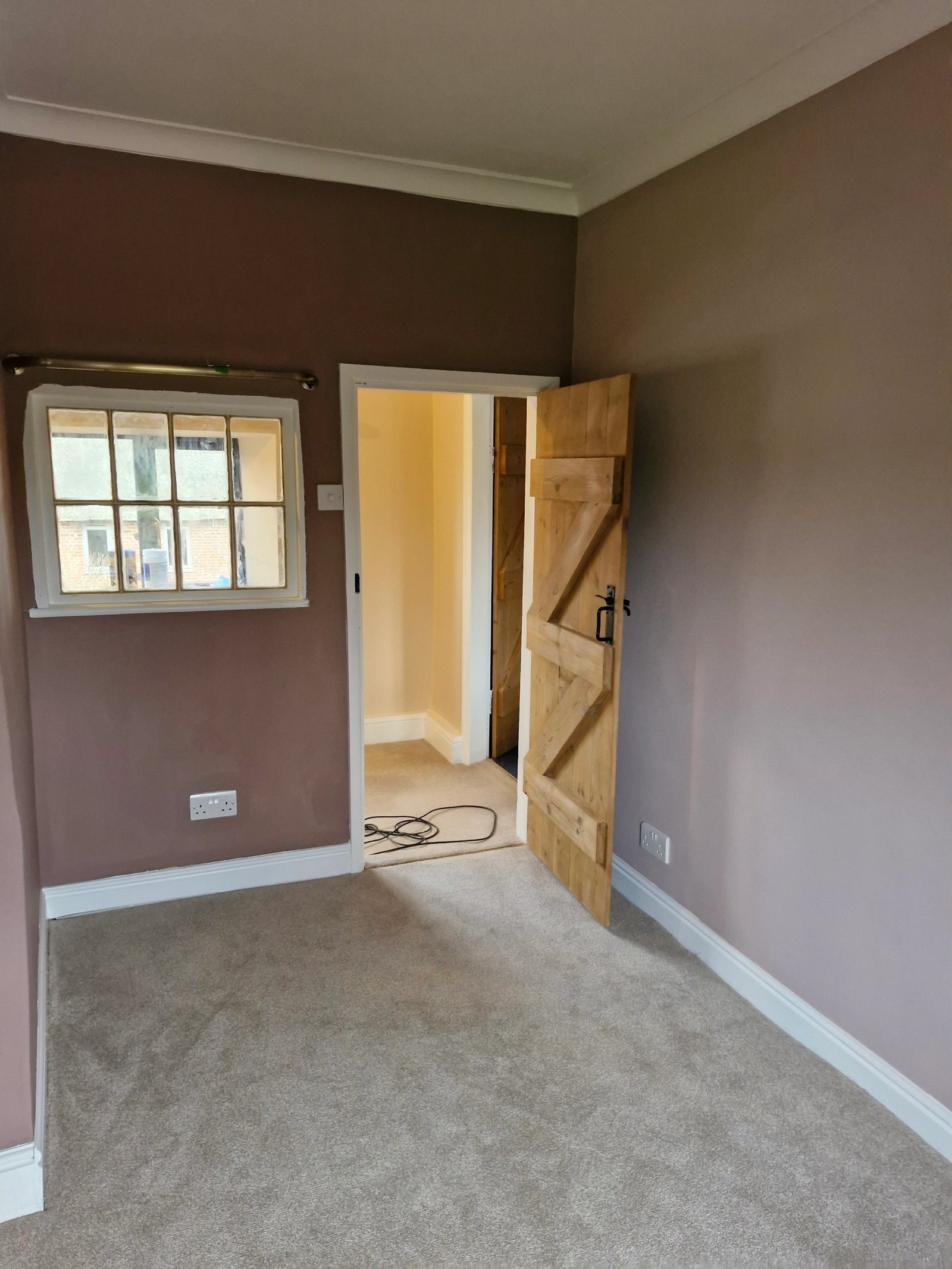 Refurbished room with a stripped timber door, new carpet and painted walls