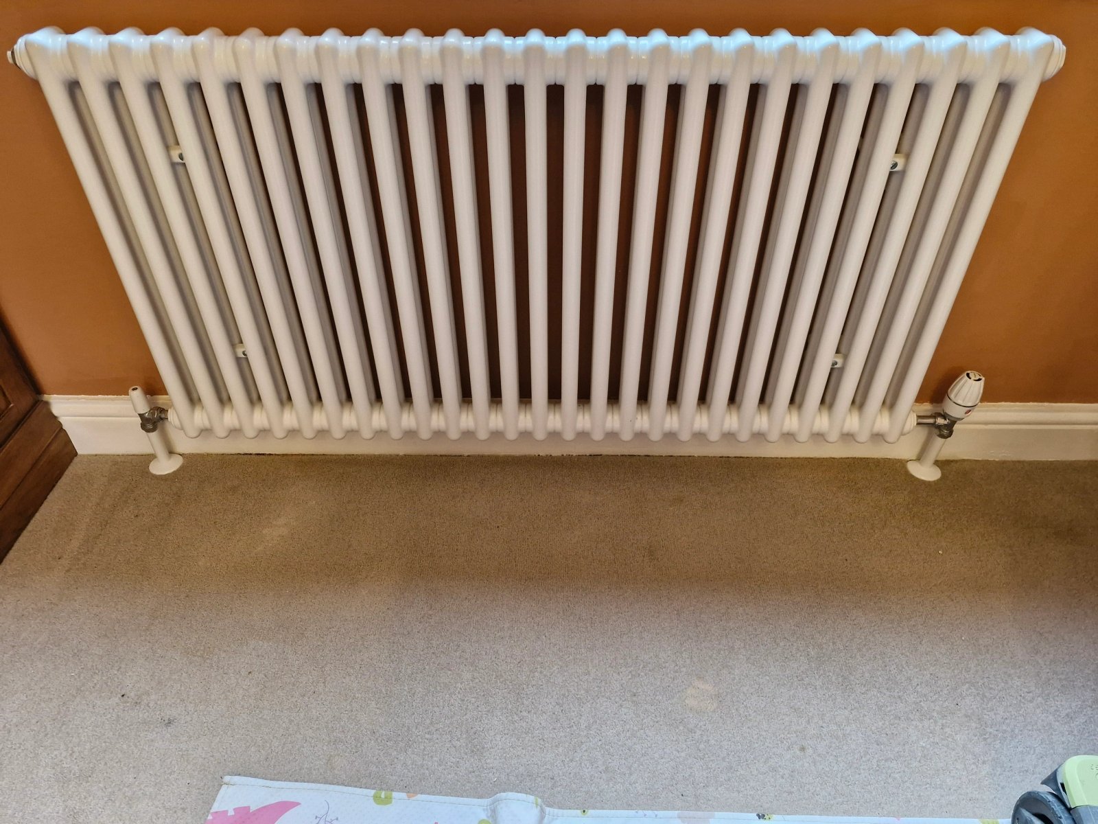 Large white column radiator fitted to a wall in a refurbished reception room