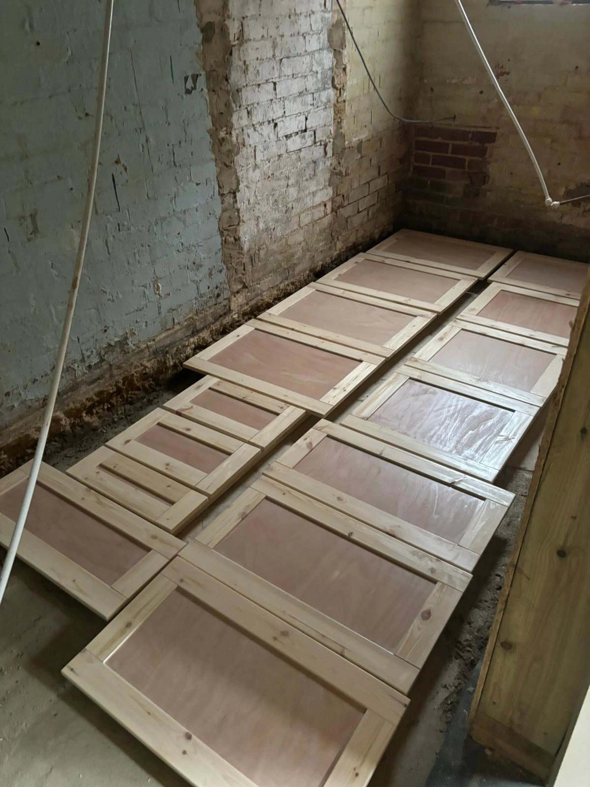 Kitchen cabinet doors laid out flat on trestles in a workshop ready for finishing