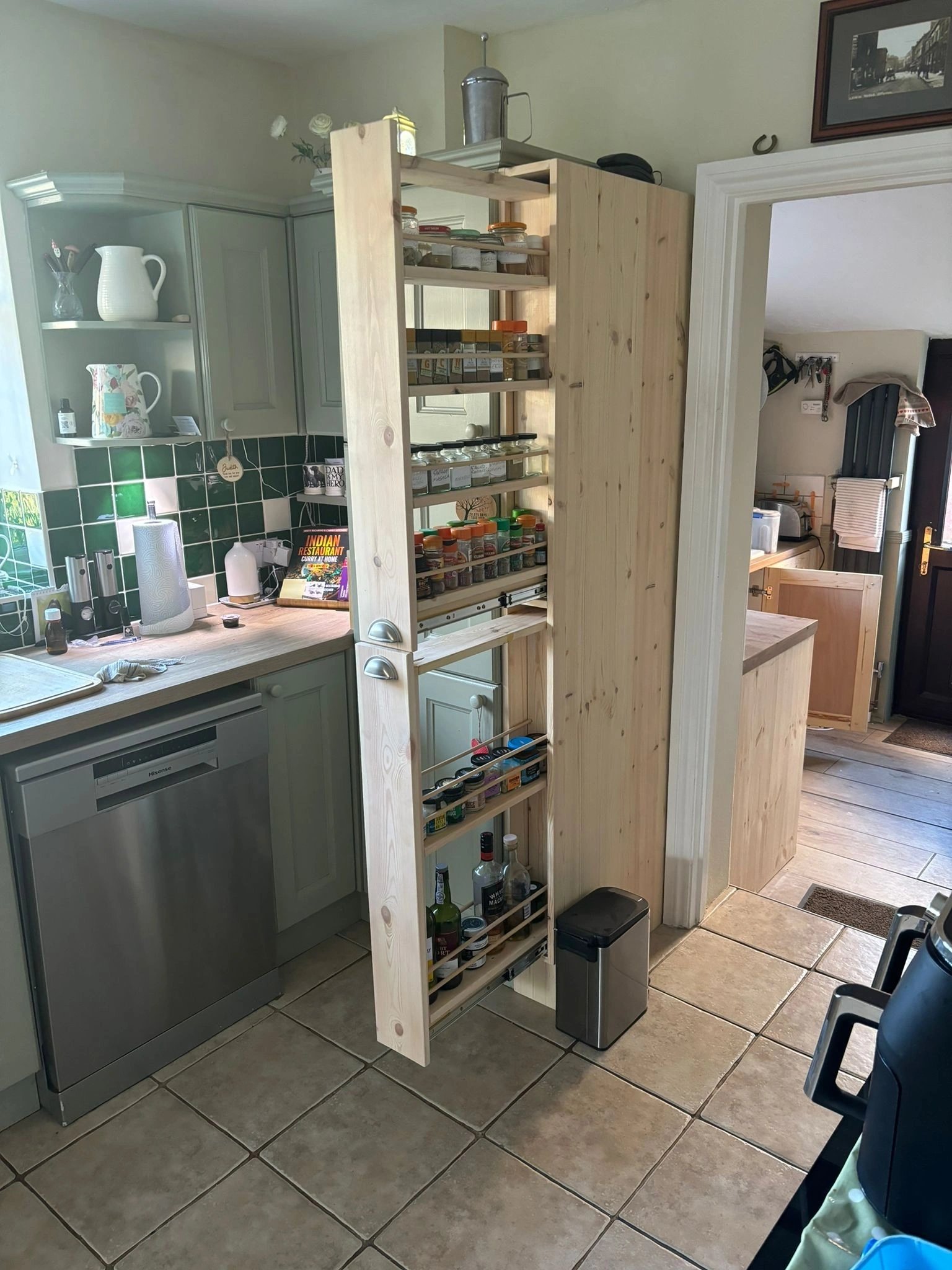 Grey fitted kitchen with a tall pull-out larder unit open to show shelves of provisions