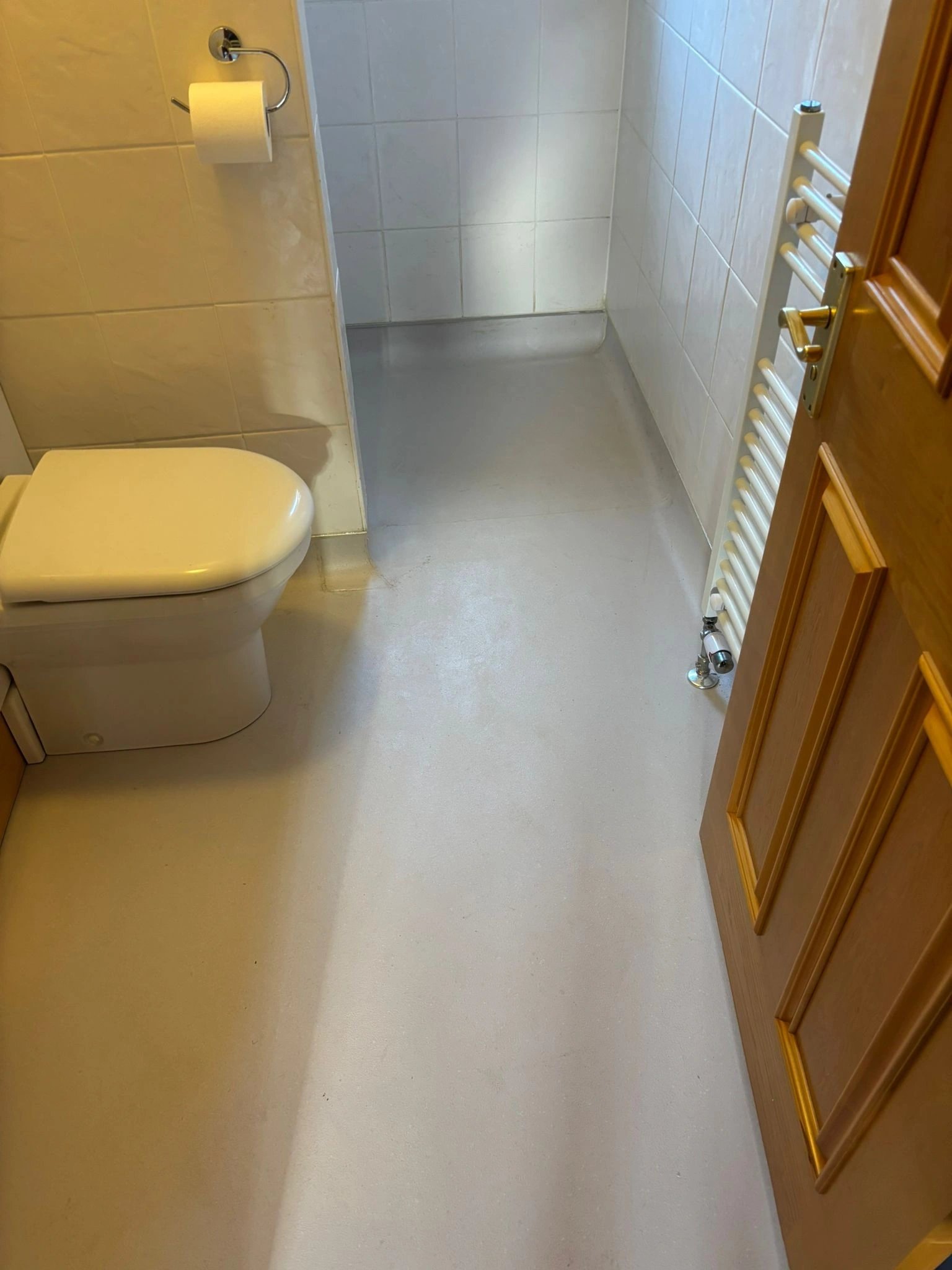 Fitted bathroom with wall-hung WC, tiled floor and chrome towel radiator