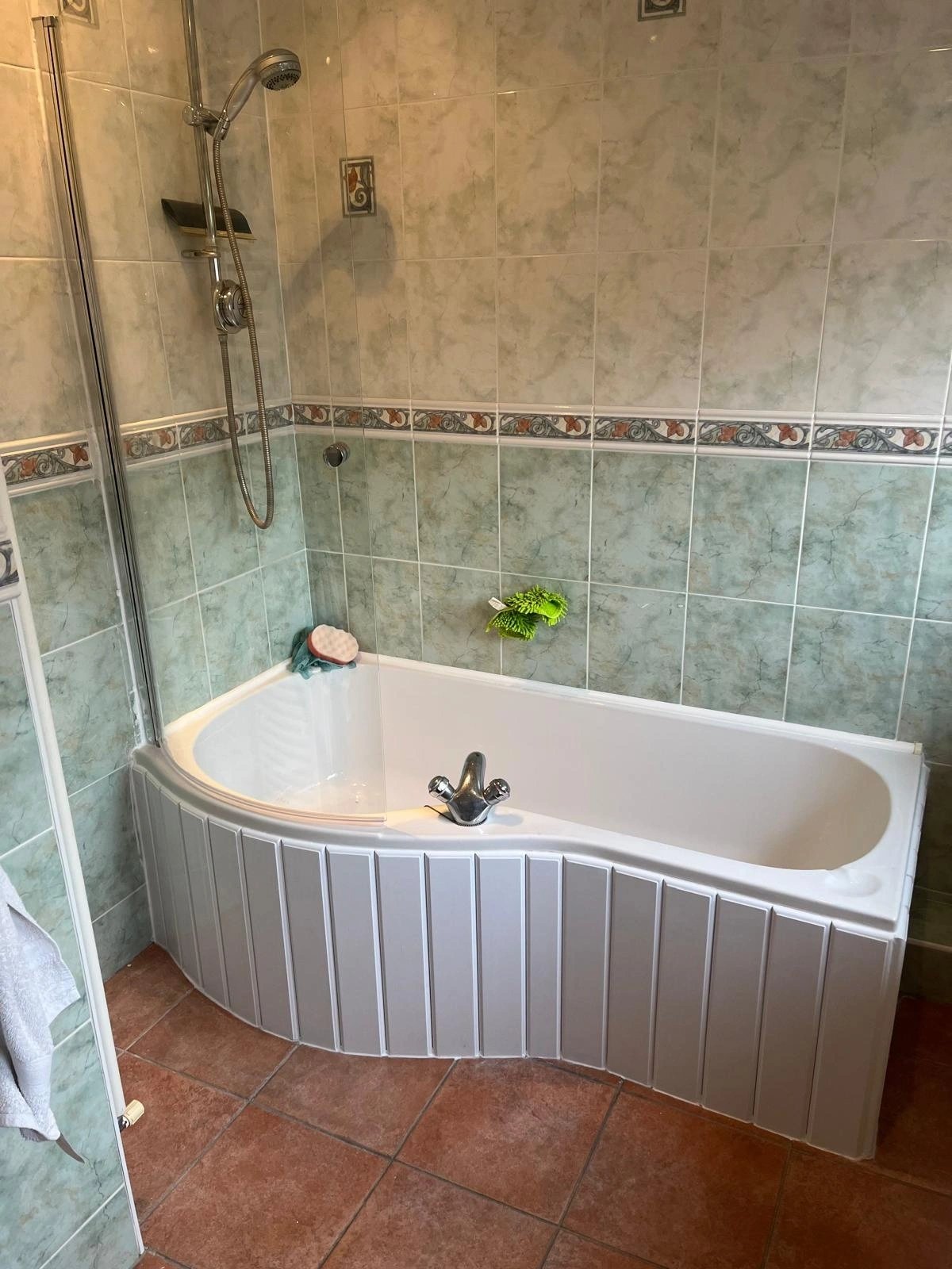 Corner bath with shower over and tiled surround in a family bathroom