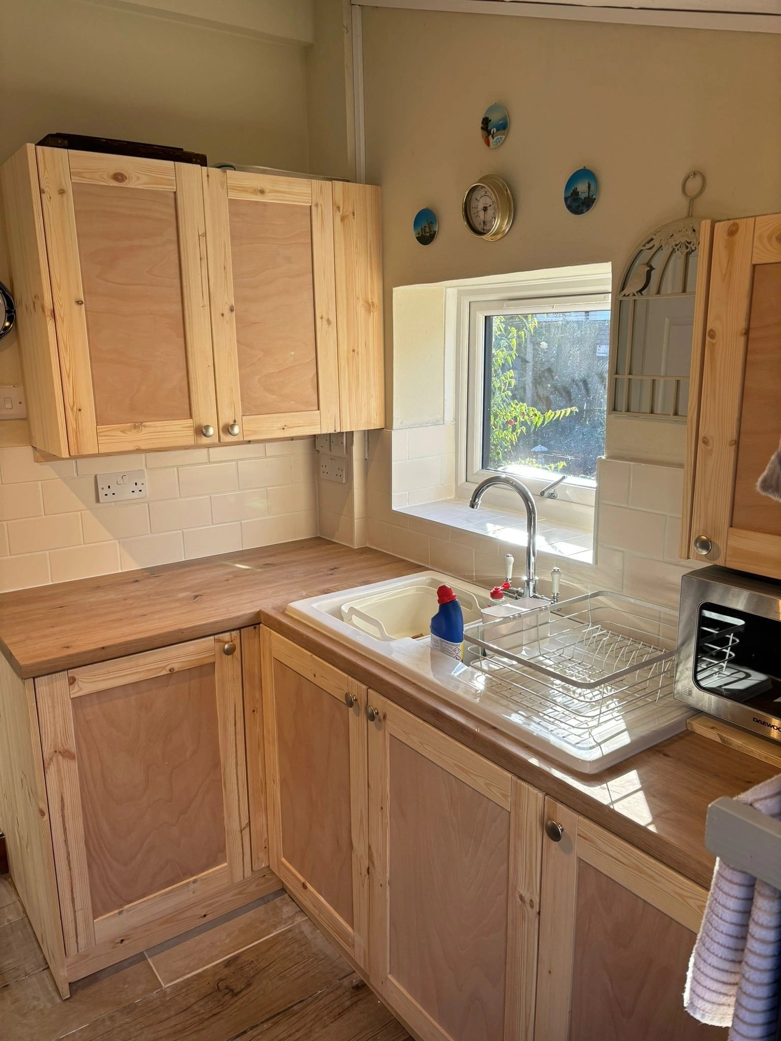 Kitchen wall and base units in light timber either side of a window