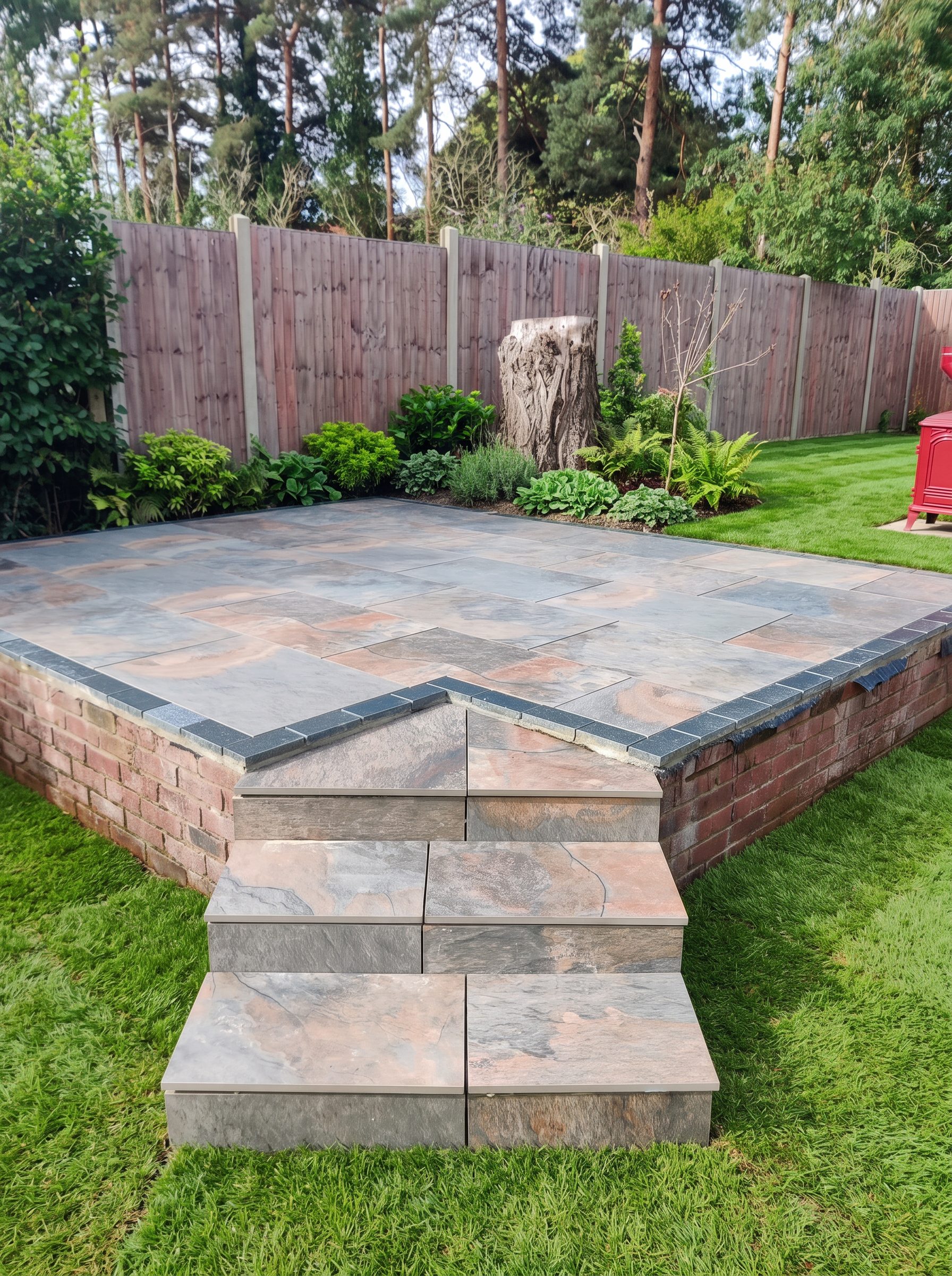 Raised Indian stone patio with steps and brick edging built by Acorn in a Norfolk garden